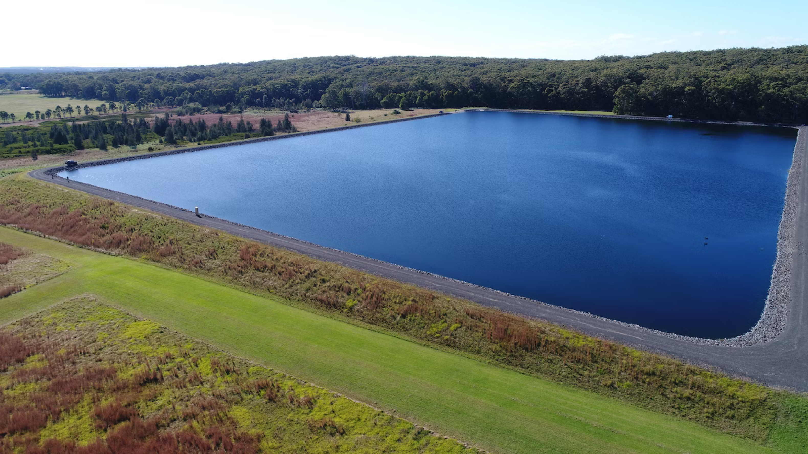 An aerial photo of the rems storage dam. It is a large body of water surrounded by trees and vegetation.