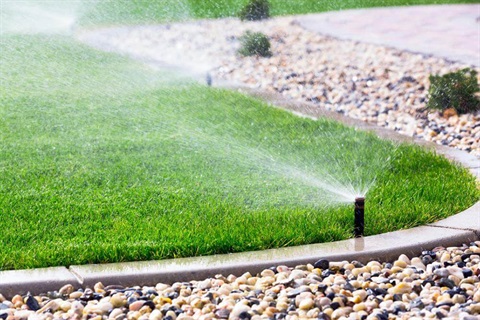 A photo of a garden water sprinkler spraying water onto a grass lawn.